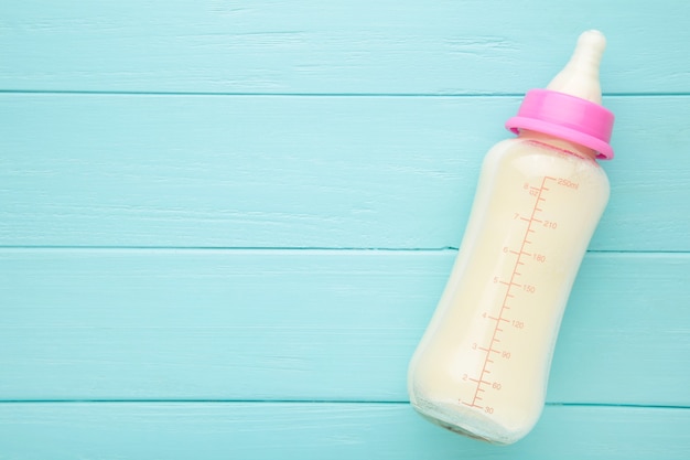 Mise à plat gros plan sur la bouteille de lait pour bébé sur fond bleu