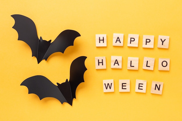 Mise à plat d'Halloween avec texte Happy Halloween et deux chauves-souris volantes sur fond jaune - Image