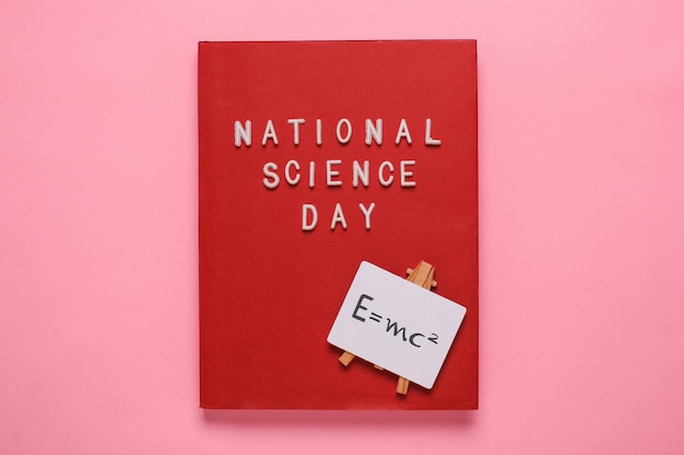 Photo mise à plat de la journée nationale de la science écrivant sur un livre rouge avec une formule einsten sur une pancarte