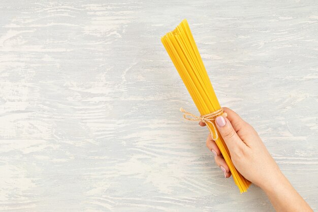 Mise à plat de la main de femme tenant des spaghettis pour la cuisson des pâtes italiennes. Vue de dessus du concept de cuisine italienne traditionnelle