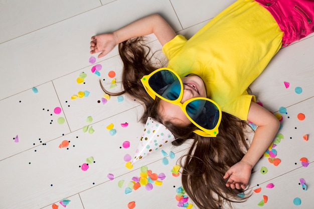 Photo mise à plat de mignonne petite fille avec de grandes lunettes de soleil