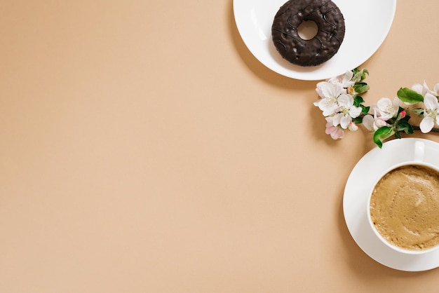 Mise à plat à la mode d'un petit-déjeuner indépendant avec café et beignets sucrés sur fond beige