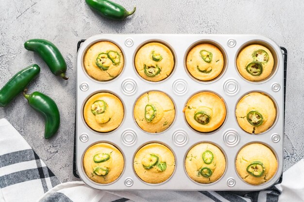 Mise à plat. Muffins au pain de maïs fraîchement cuits avec piment jalapeno épicé dans un moule à muffins.