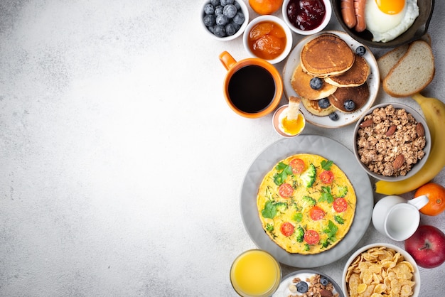 Mise à plat d'omelette et de crêpes pour le petit déjeuner avec des céréales et de la confiture