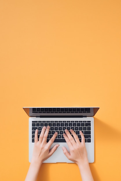 Mise à Plat D'un Ordinateur Portable, D'un Café Et D'un Ordinateur Portable Sur Fond Jaune. Mains Féminines Tapant Sur Le Clavier