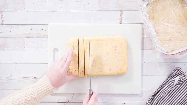 Mise à plat. Pas à pas. Couper le fudge de canne en bonbon fait maison sur une planche à découper blanche.