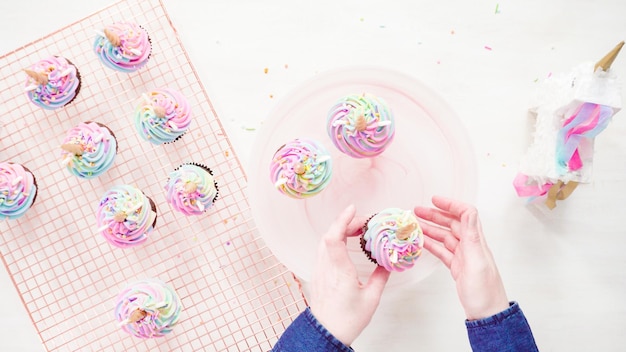 Mise à plat. Pas à pas. Cuisson de cupcakes au chocolat licorne avec glaçage à la crème au beurre de couleur arc-en-ciel.