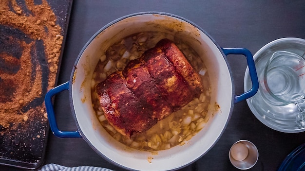 Mise à plat. Pas à pas. Cuisson du rôti de porc désossé dans un four hollandais en fonte.