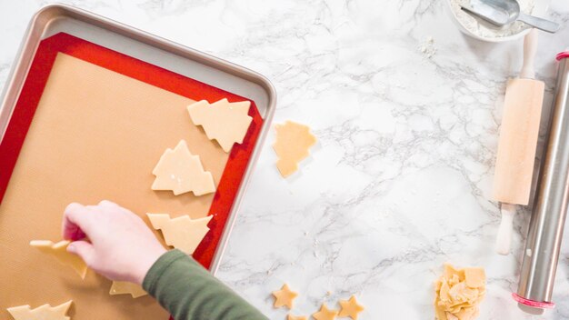 Mise à plat. Pas à pas. Découper des formes avec un emporte-pièce pour biscuits de Noël dans de la pâte à biscuits au sucre.