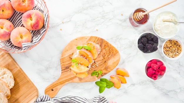 Mise à plat. Pas à pas. Faire des toasts à la ricotta avec des pêches et des baies biologiques.