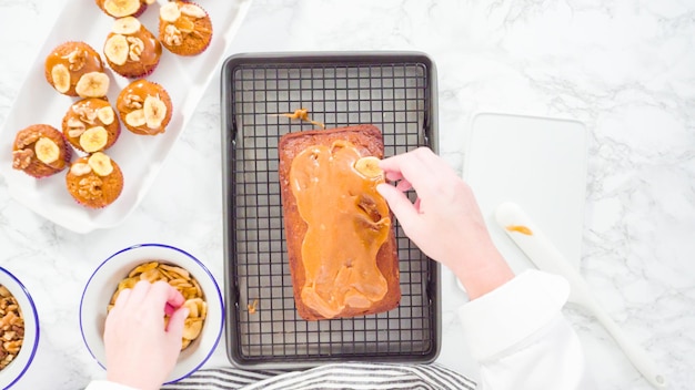 Photo mise à plat. pas à pas. garnir le pain aux bananes avec du caramel maison, des chips de banane et des noix.