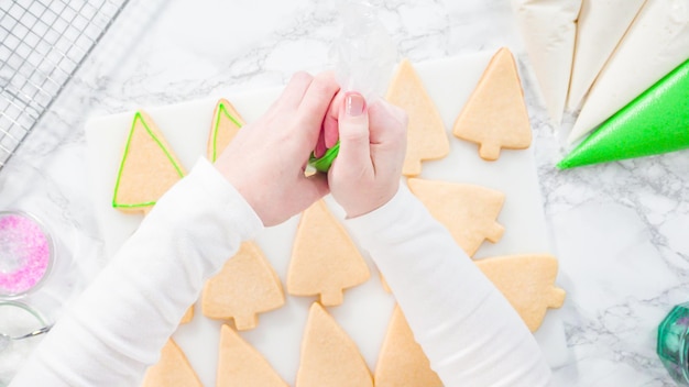 Mise à plat. Pas à pas. Glaçage biscuits au sucre en forme de sapin de Noël avec glaçage royal vert.