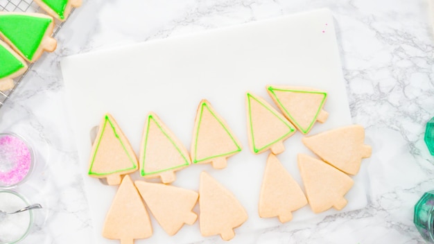 Mise à plat. Pas à pas. Glaçage biscuits au sucre en forme de sapin de Noël avec glaçage royal vert.