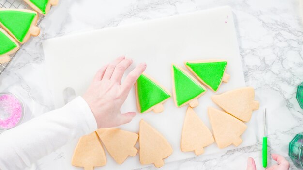 Mise à plat. Pas à pas. Glaçage biscuits au sucre en forme de sapin de Noël avec glaçage royal vert.