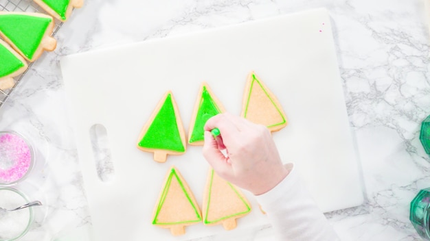 Mise à plat. Pas à pas. Glaçage biscuits au sucre en forme de sapin de Noël avec glaçage royal vert.