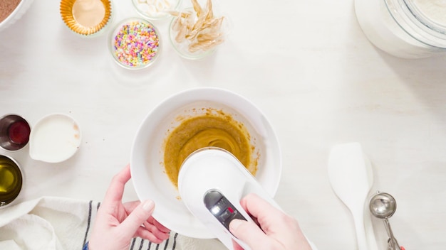 Mise à plat. Pas à pas. Mélanger les ingrédients ensemble dans un bol à mélanger blanc pour faire des cupcakes au chocolat licorne avec un glaçage à la crème au beurre.