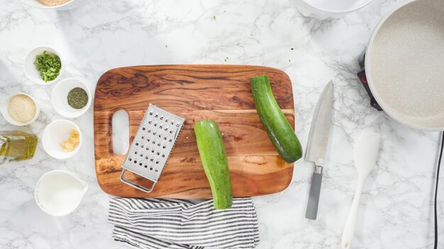 Mise à plat. Pas à pas. Râper des courgettes bio pour faire des galettes de courgettes.