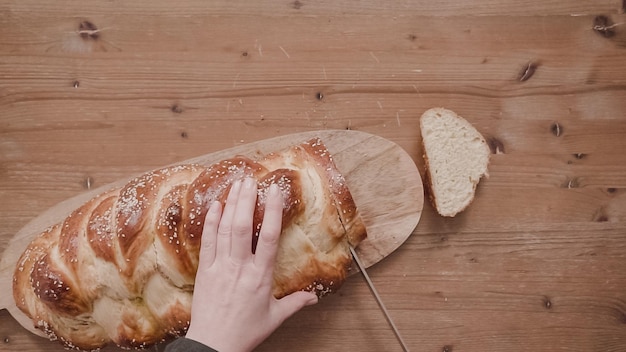 Mise à plat. Pas à pas. Trancher du pain shallah fraîchement cuit au four avec des graines de sésame et de pavot.