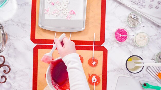 Mise à plat. Pas à pas. Verser du sucre caramélisé sur un tapis de cuisson en silicone pour réaliser des sucettes maison.