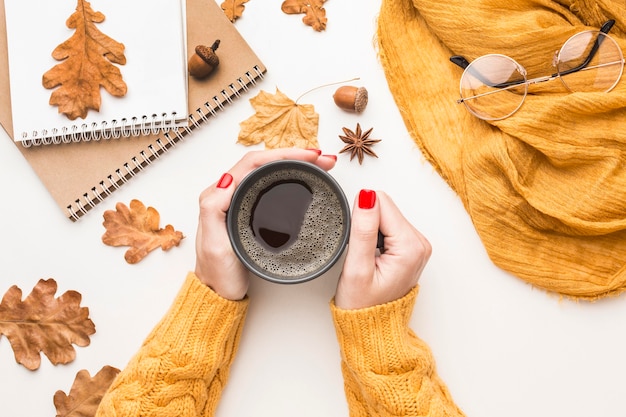 Photo mise à plat de personne tenant une tasse de café avec des feuilles d'automne