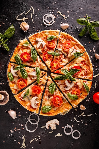 Photo mise à plat avec pizza italienne sur fond noir et divers ingrédients