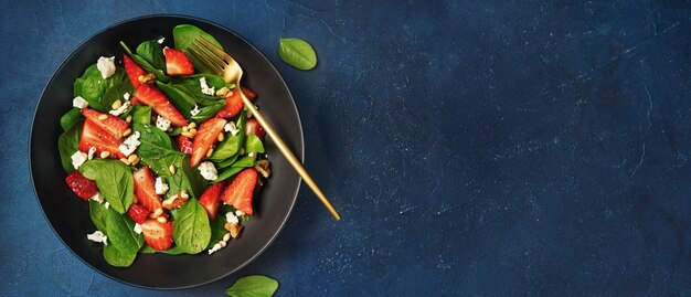 Mise à plat de plaque noire avec salade de fraises et d'épinards