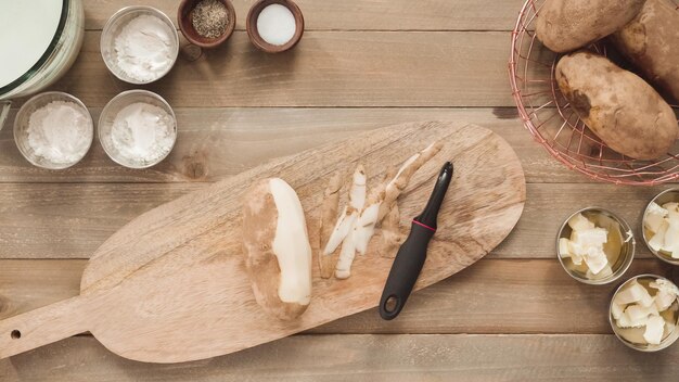 Mise à plat. Éplucher les pommes de terre jaunes biologiques avec un éplucheur de pommes de terre.