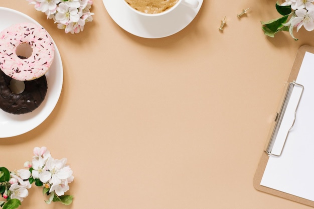 Mise à plat de printemps avec des fleurs de pommier Lieu de travail de la femme Pause thé avec Donut Copier l'espace