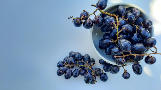 Mise à plat, raisins violets dans un bol avec tige isolé sur fond blanc 01