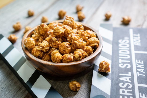 Mise à plat de savoureux pop-corn au caramel et clap sur table en bois close up concept de temps de film