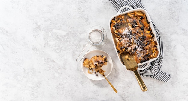 Mise à plat Servir du pudding au pain fraîchement cuit avec des tranches de pain et d'amandes dans une cocotte blanche