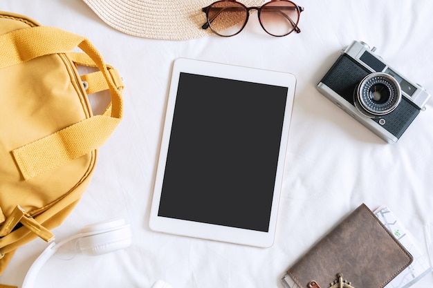 Mise à plat de la tablette et des accessoires de voyage avec chapeau de plage, lunettes de soleil, sac à dos, appareil photo