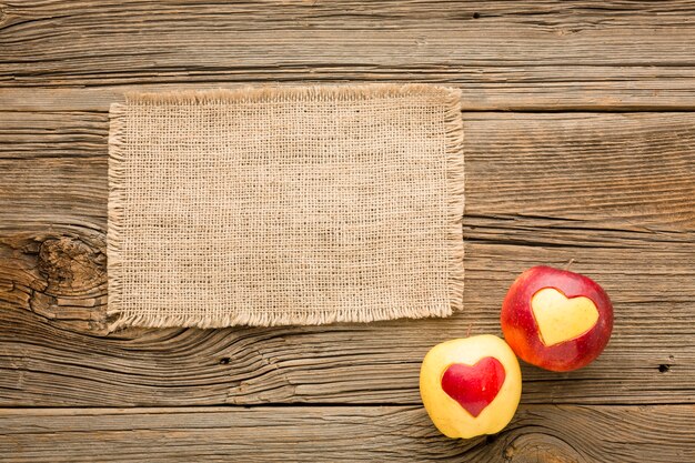 Photo mise à plat de tissu et de pommes avec des formes de coeur de fruits