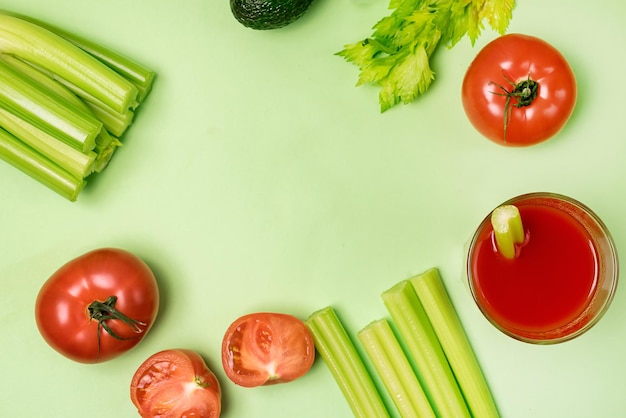 Mise à plat avec verre de tomates savoureuses et saines et jus de céleri tomates crues céleri et avocat