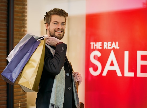 En mission de chasse aux bonnes affaires Portrait d'un jeune homme heureux lors d'une virée shopping