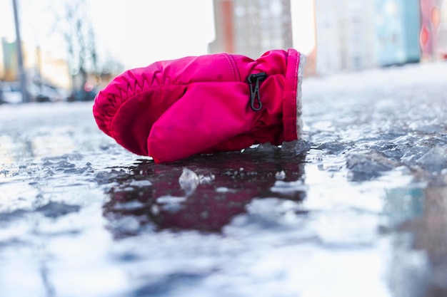 Une mitaine d'enfant sur une route glissante faite de glace fondue Dégel printanier et verglas Route hivernale en ville Blessures et conséquences après une chute sur une route verglacée