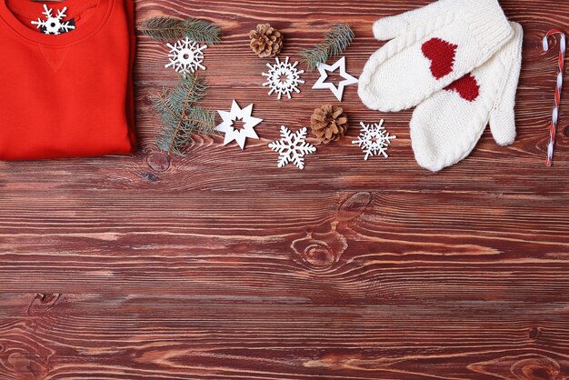 Mitaines de chandail rouge et décor de Noël sur fond de bois