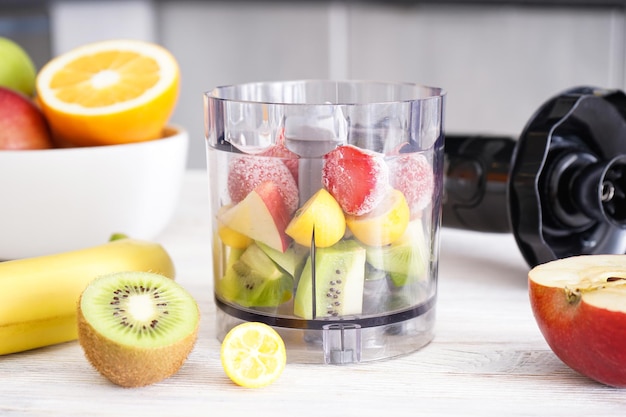 Un mixeur plongeant et une table de fruits mûrs pour cuisiner à la maison.