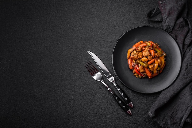 Photo mixture de légumes, de maïs, de carottes, de poivrons, de brocolis, d'oignons dans une sauce teriyaki sur une assiette en céramique sur un fond en béton sombre