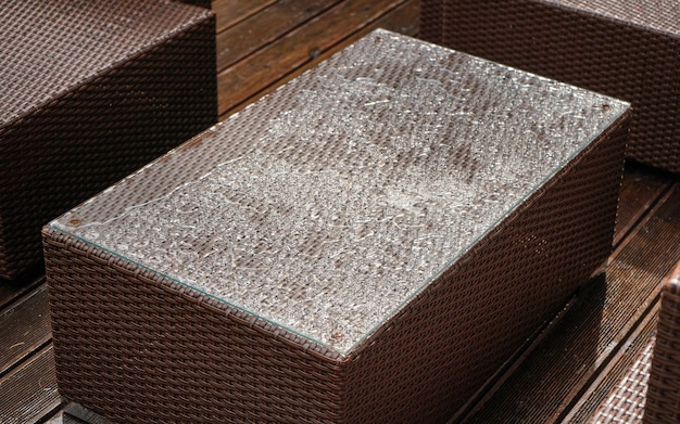 Mobilier de jardin en rotin artificiel brun simple, dessus recouvert de gouttes de pluie, gros plan détail