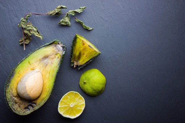 Moche Avocat Pourri Sur Ardoise. Bad Citron Vert Et Menthe Sèche Sur Ardoise Noire. Fruits Tropicaux Pourris. Concept De Fruits Pourris