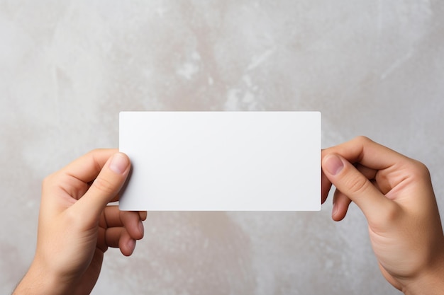 Mockup d'une carte de visite blanche dans les mains d'une femme sur un fond gris