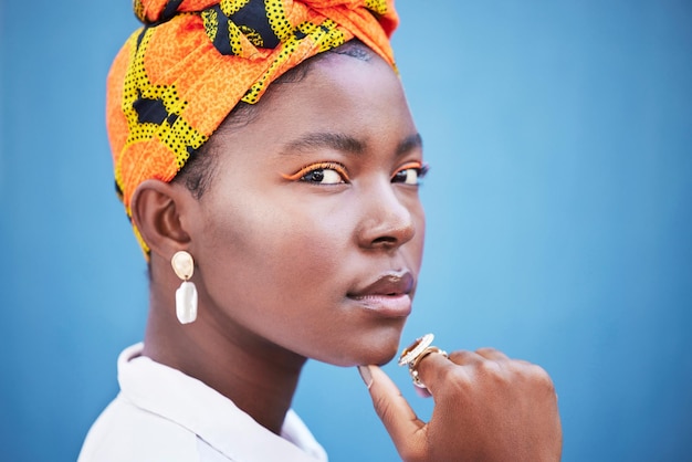 Mode africaine et portrait de femme noire sur fond bleu avec foulard peau et maquillage éclatants Beauté glamour et visage de modèle féminin avec bijoux de style exotique et cosmétiques en studio