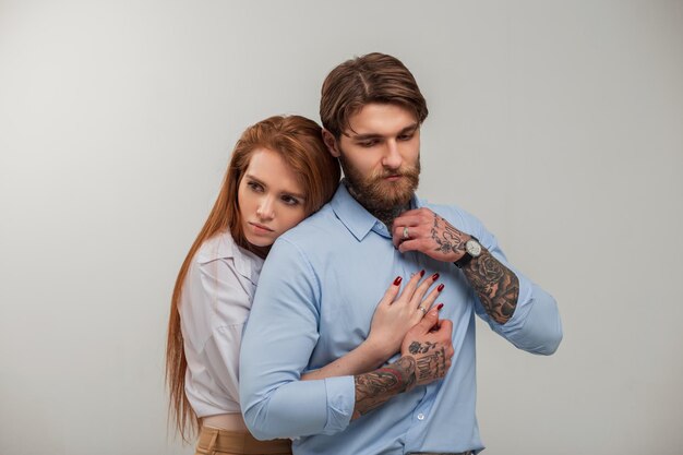 À la mode beau couple élégant dans des vêtements élégants sur fond blanc Jolie fille rousse embrasse un bel homme brutal