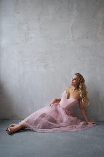 Mode belle femme vêtue d'une robe assise sur le sol contre le mur