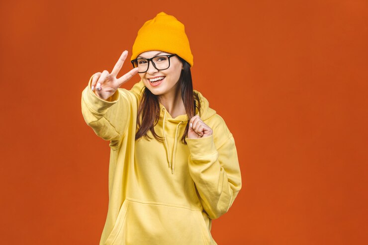 Photo à la mode belle jeune caucasienne jeune étudiante portant des vêtements élégants en riant, en pointant le doigt. isolé sur orange.