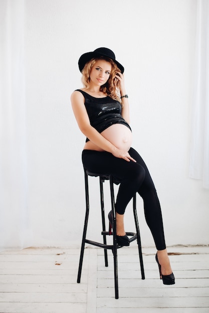 À la mode et blonde femme enceinte portant un chapeau noir