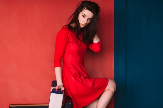 mode, brunette, femme, dans, robe rouge, poser, dans, mur rouge