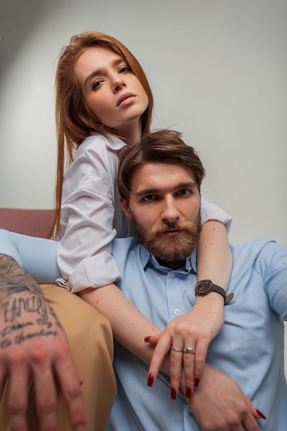 Mode cool beau jeune couple qui pose en studio Belle fille modèle rousse étreignant brutal beau mec hipster avec barbe et tatouage