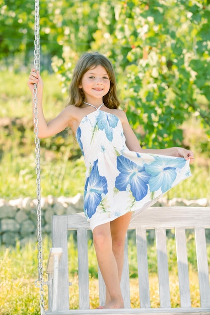 Mode enfants s'habillent petite fille enfant se balance sur une balançoire dans le parc d'été journée d'été joyeuse ensoleillée c